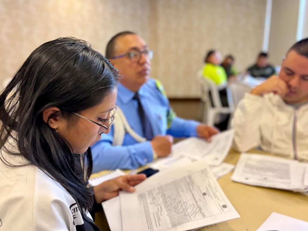 Funcionarios y autoridades de tránsito en Nariño revisando documentos y borradores de comparendos durante una jornada de capacitación técnica.