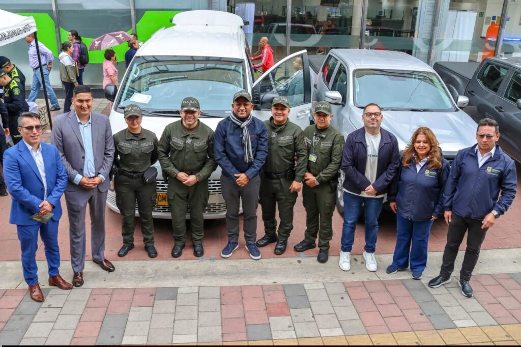 El Gobernador de Nariño, Luis Alfonso Escobar, junto a miembros de la Policía Nacional y funcionarios frente a una van blanca y una camioneta gris entregadas para la seguridad.