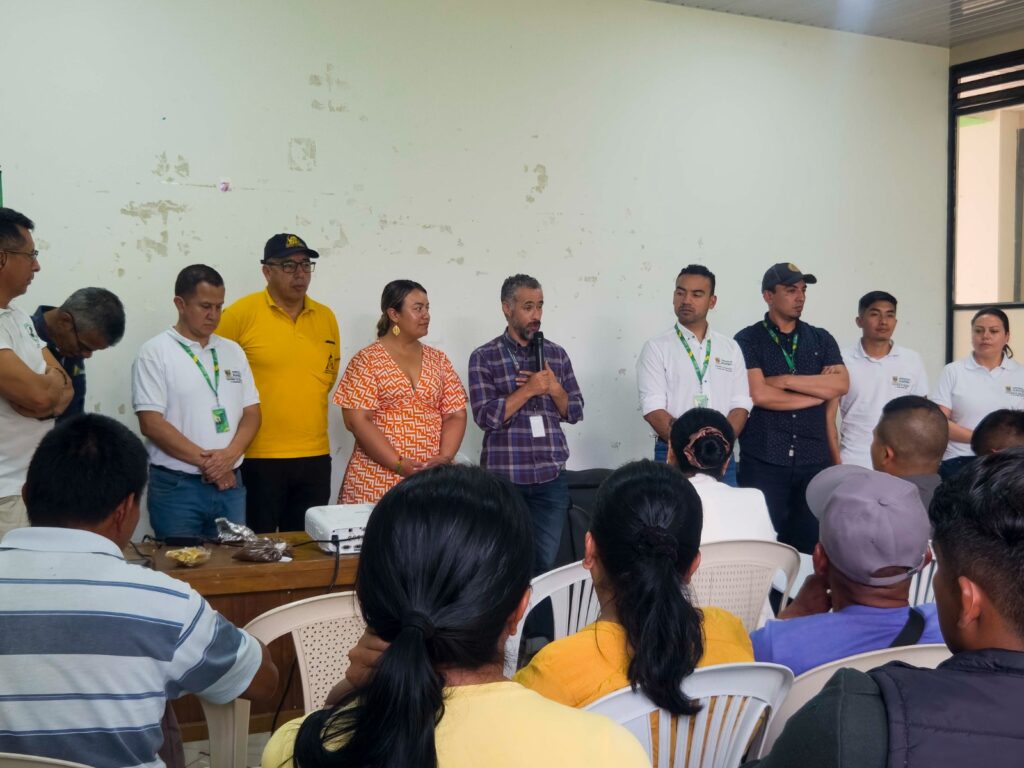 Panel de expertos y funcionarios durante el conversatorio "Paz con Aroma de Café" en Ricaurte, escuchando la intervención de un ponente frente a la comunidad.