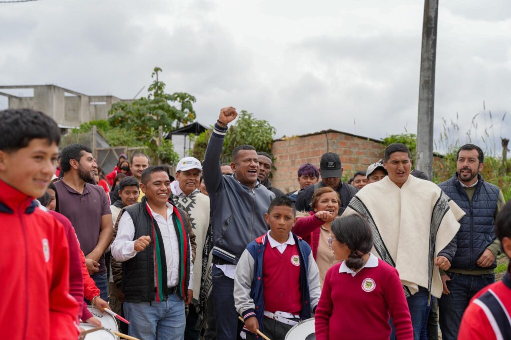 El Gobernador de Nariño, Luis Alfonso Escobar Jaramillo, con el puño en alto en señal de victoria, rodeado por la comunidad, niños con uniformes escolares y una banda de guerra durante la jornada en Ipiales.