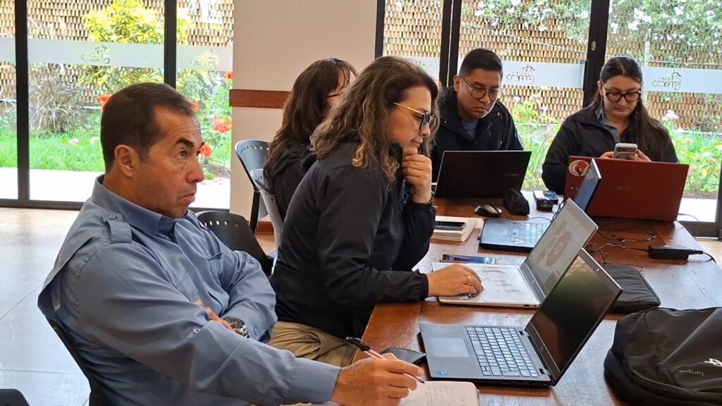 Delegados ambientales de Nariño y Ecuador participan en una mesa técnica de trabajo con computadores portátiles durante el taller binacional de "Gestión de Áreas Protegidas y Ecosistemas Estratégicos".