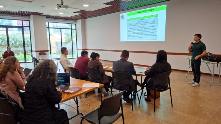 Un expositor presenta la agenda del "Taller Binacional" sobre gestión de áreas protegidas ante delegados de Nariño y Ecuador, destacando temas como ecosistemas estratégicos y gobernanza ambiental.