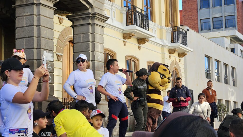 Personas y una botarga frente al edificio de la Gobernación de Nariño para la carrera "Al Ritmo de mi Voz".  