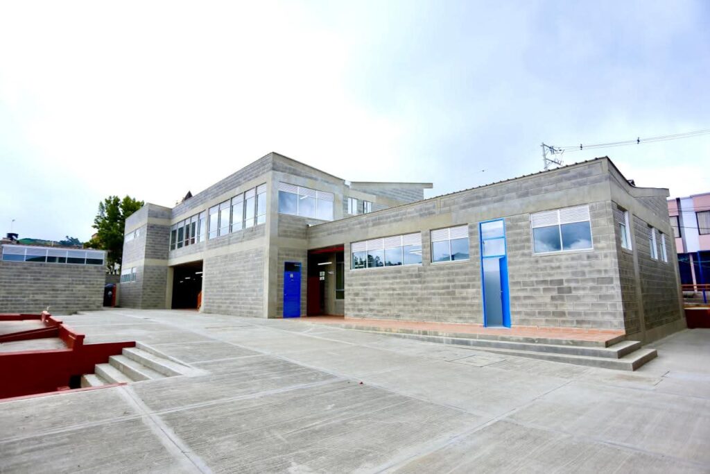 Fachada moderna de la Institución Educativa Instituto Teresiano en Túquerres, construida con bloques de concreto gris, amplios ventanales y puertas azules bajo un cielo despejado.