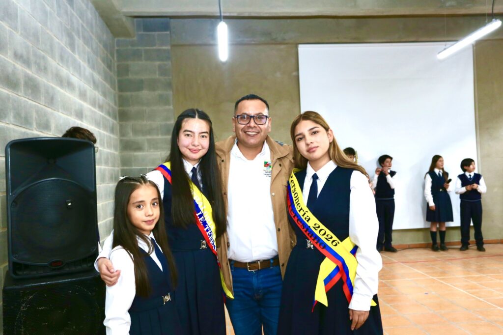 El Secretario de Educación de Nariño, Adrian Zeballos, posando junto a tres estudiantes de la Institución Educativa Instituto Teresiano en Túquerres; dos de ellas portan bandas tricolores de personería y consejo estudiantil.