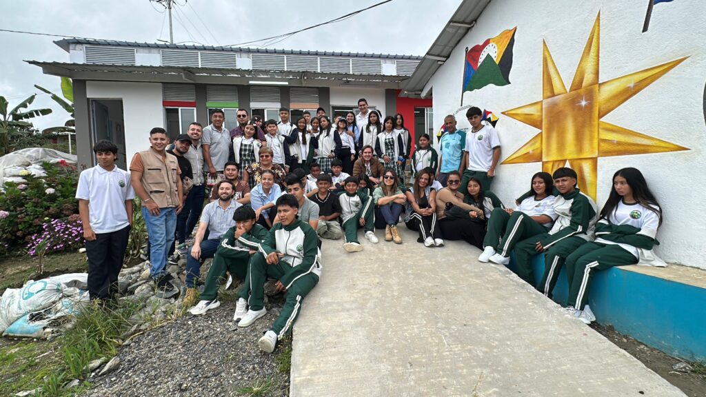 Un gran grupo de personas, incluyendo estudiantes de la etnia Awa , profesores, funcionarios de la Gobernación de Nariño y del Gobierno Nacional , posan para una foto comunitaria frente a una nueva aula de la Institución Educativa Betania. Entre los asistentes se encuentra Alex Javier González, secretario de Paz y Derechos Humanos de Nariño
