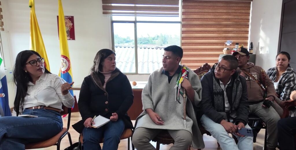 Dialogo en una mesa de trabajo con líderes comunitarios y una autoridad indígena que porta su bastón de mando en Aldana.