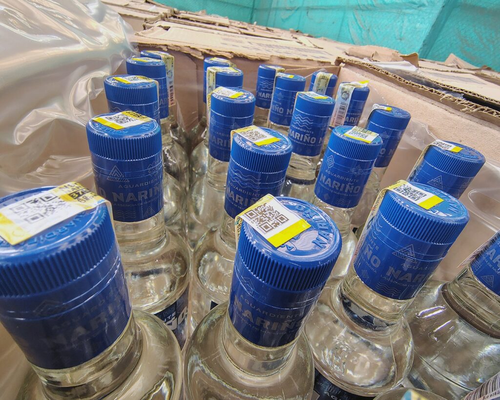 Primer plano de las tapas azules y estampillas de rentas departamentales en botellas de Aguardiente Nariño Sin Azúcar.