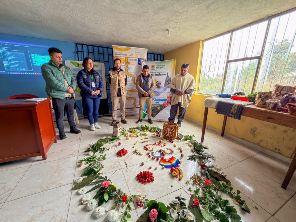 Integrantes de la Dirección Administrativa de Turismo de Nariño y líderes del Resguardo El Gran Cumbal en una jornada de formación, rodeando un círculo ceremonial de armonización con elementos naturales y artesanías.