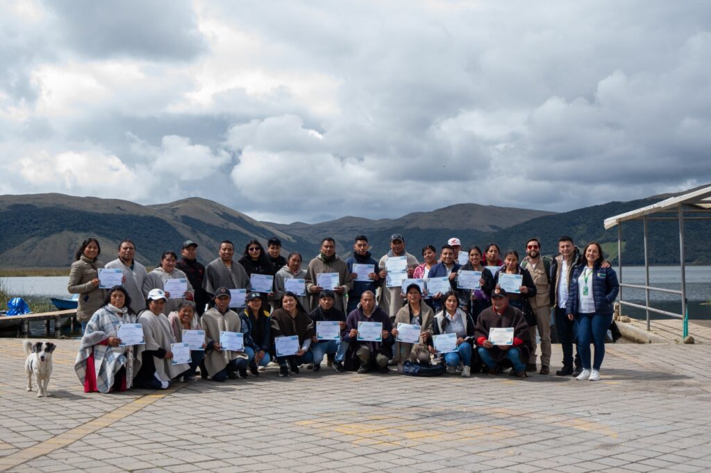 Grupo de líderes y emprendedores del Resguardo Indígena El Gran Cumbal posan con sus certificados de formación turística a orillas de la Laguna de La Bolsa, acompañados por funcionarios de la Gobernación de Nariño.