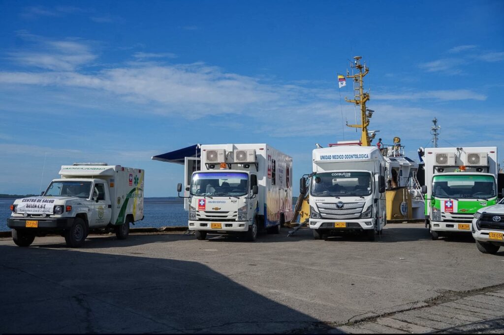 Ambulancia del Centro de Salud Belén E.S.E. y unidades médicas odontológicas terrestres estacionadas en un muelle junto a un barco de la misión médica.