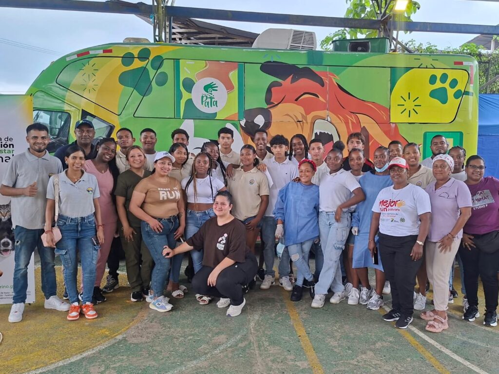 Foto grupal de jóvenes, veterinarios y líderes comunitarios frente a la unidad móvil "Dales una Pata" de la Gobernación de Nariño en una jornada de bienestar animal.