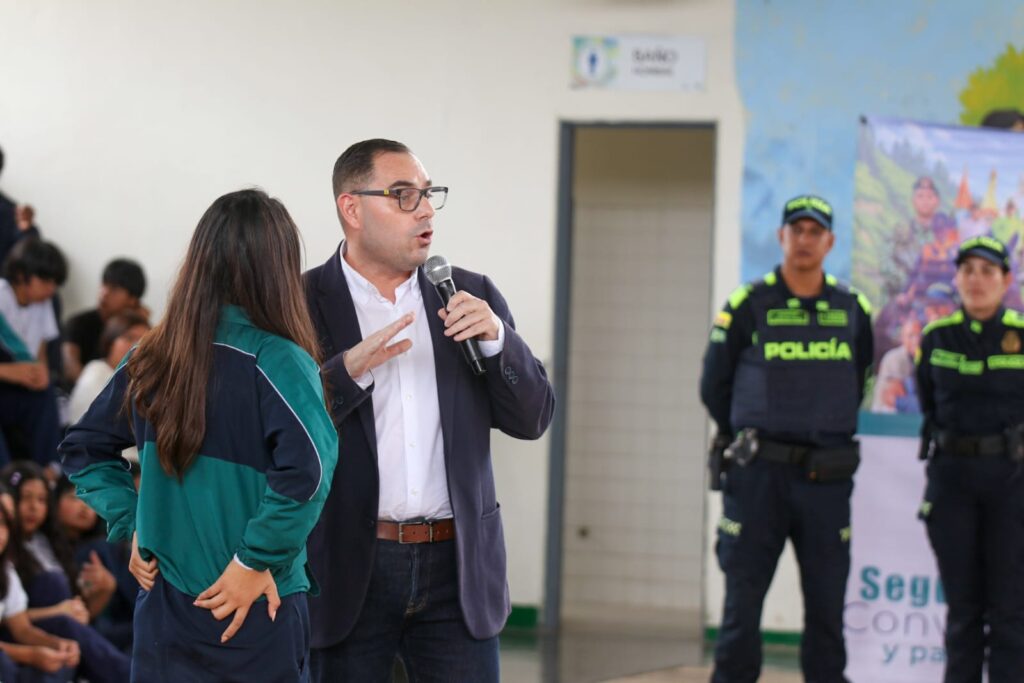 El Subsecretario de Seguridad Ciudadana de Nariño, Andrés Peñaranda, habla con un micrófono frente a una estudiante del INEM de Pasto en la jornada de convivencia escolar.