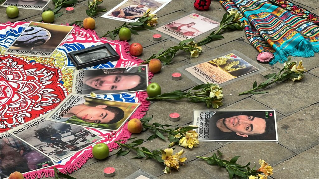 Altar con fotografías de personas desaparecidas, flores amarillas, manzanas y velas en el encuentro de la Secretaría de Paz en Nariño.