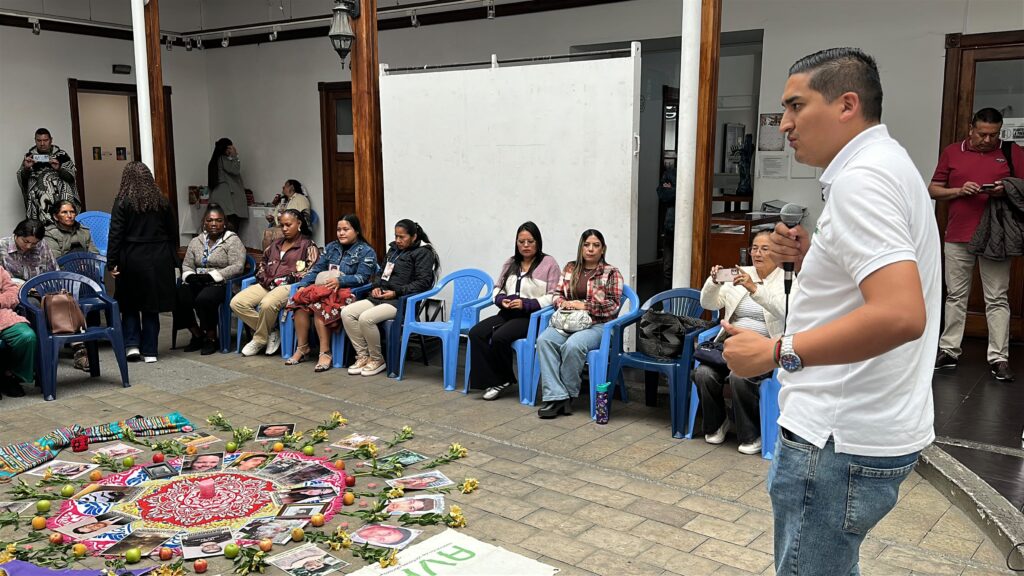 Intervención de un funcionario ante un grupo de mujeres buscadoras y firmantes de paz sentadas en un patio durante un encuentro institucional de la Secretaría de Paz.