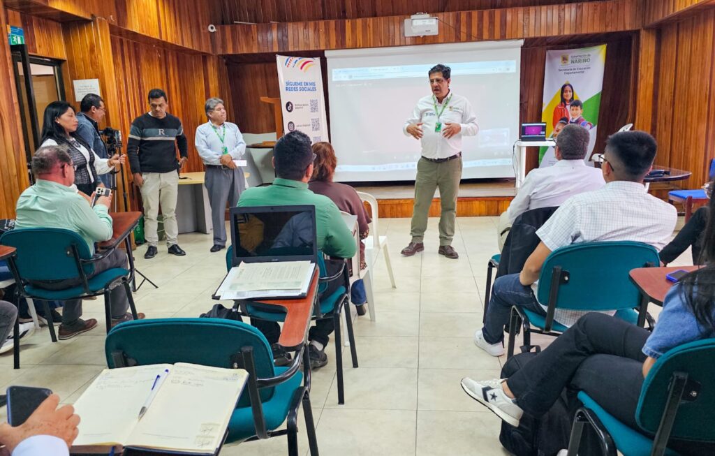 Auditorio institucional con paredes de madera donde Rodrigo Duque, Coordinador Nariño Superior, expone la estrategia de doble titulación frente a rectores y delegados de educación de Nariño sentados con carpetas y apuntes.