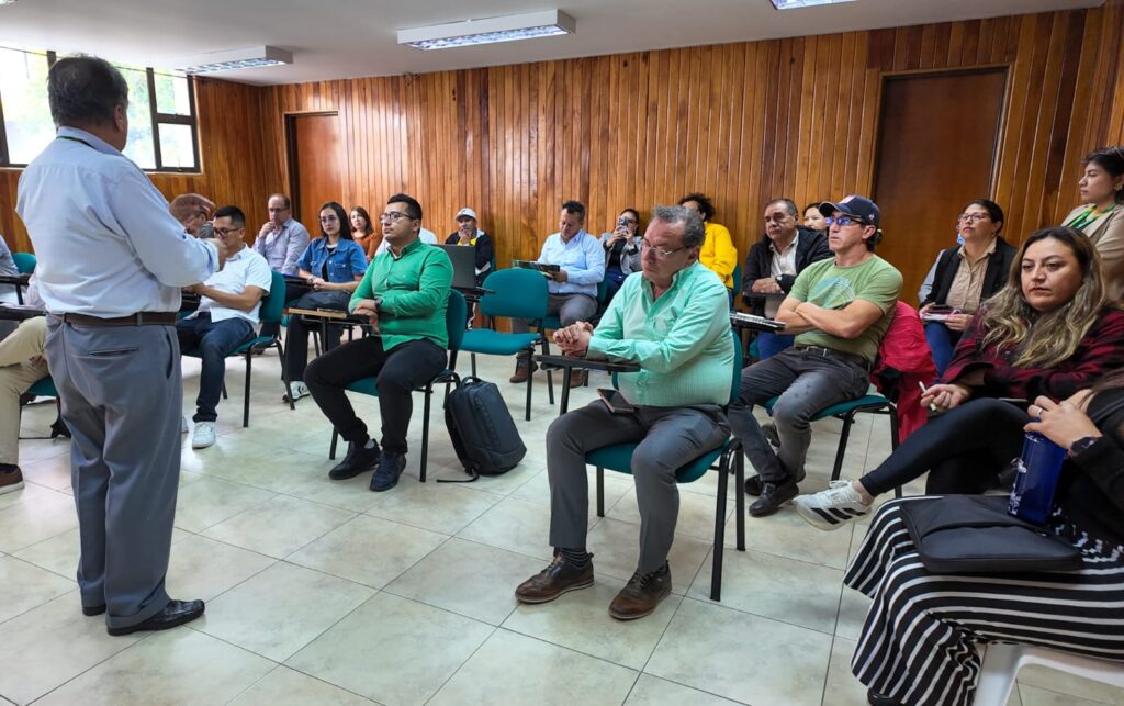 Plano lateral de rectores y directivos de instituciones agropecuarias de Nariño prestando atención a la ronda de preguntas en un auditorio con acabados de madera.