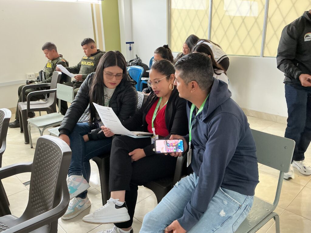 Asistentes y miembros de la Policía Nacional revisan documentos normativos durante la jornada pedagógica de la estrategia "Juega Legal y Construye Paz"