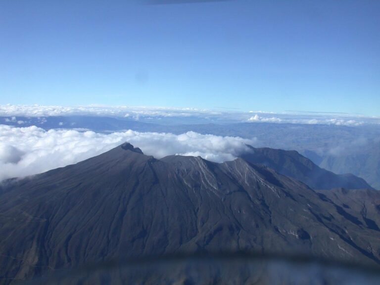 Panorámica aérea del Volcán Galeras rodeado de un colchón de nubes bajo un cielo despejado, zona de influencia para el simulacro en Pasto, La Florida y Nariño.