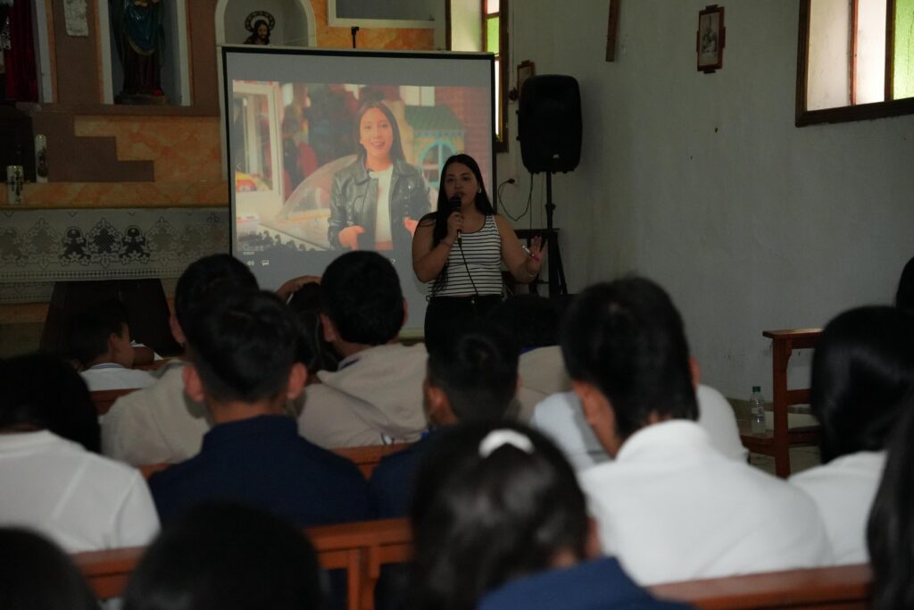 Facilitadora del Plan Departamental de Agua dirigiéndose con micrófono a un grupo de estudiantes durante una proyección educativa en Nariño.