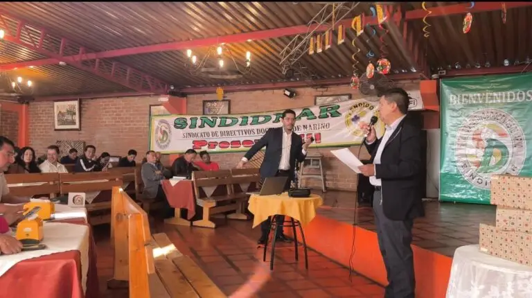 Dos ponentes intervienen con micrófono frente a los asistentes en la jornada de capacitación de Control Disciplinario Interno de la Gobernación de Nariño, con el cartel de SINDIDNAR de fondo.