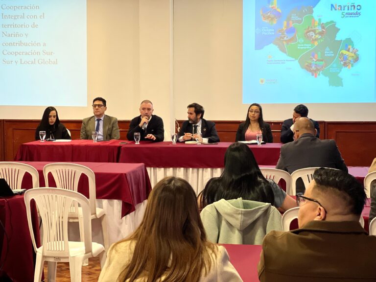 Mesa principal y asistentes en la Conferencia sobre los Nuevos Marcos de la Cooperación Descentralizada para el Desarrollo Sostenible entre Nariño y el País Vasco. Mario Lima habla al micrófono junto a Javier Cortés.