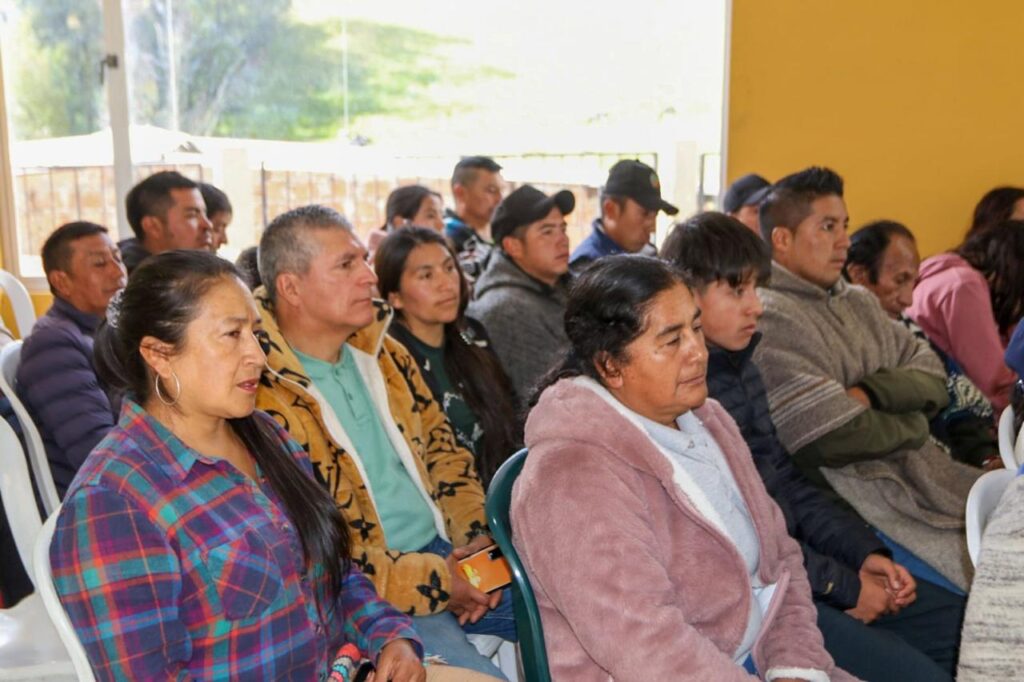 Grupo de integrantes de la Guardia Indígena del Resguardo de Iles, en su mayoría mujeres, sentados en sillas plásticas asistiendo a la capacitación técnica de producción agropecuaria.  