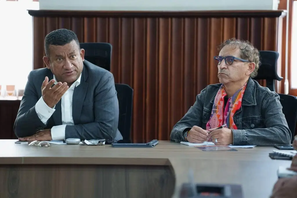Primer plano del Gobernador Luis Alfonso Escobar Jaramillo gesticulando con su mano derecha mientras expone un punto, sentado junto al Director de Cultura de Nariño, Álvaro Reyes.
