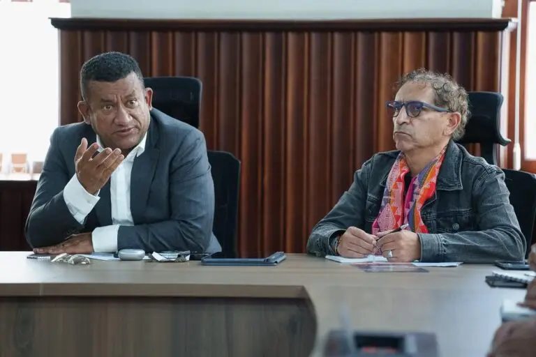 Primer plano del Gobernador Luis Alfonso Escobar Jaramillo gesticulando con su mano derecha mientras expone un punto, sentado junto al Director de Cultura de Nariño, Álvaro Reyes.