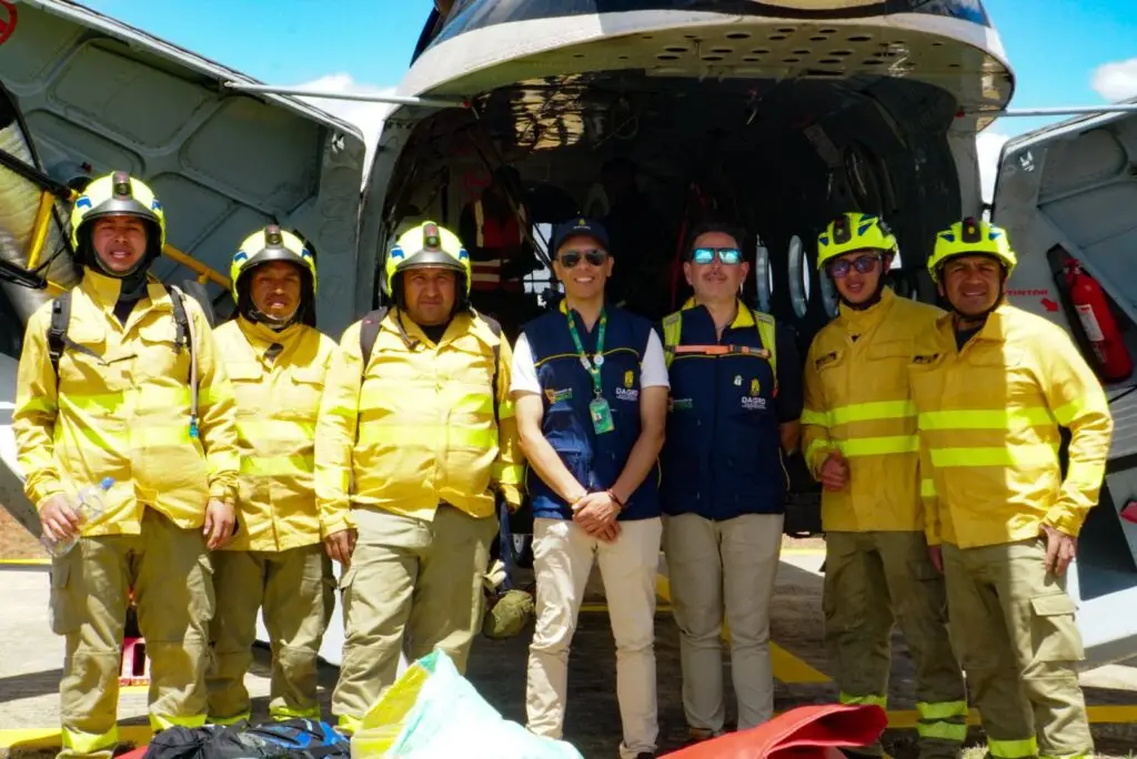 Integrantes de la Dirección Administrativa de Gestión del Riesgo de Desastres de Nariño (DAGRD) y unidades del Cuerpo de Bomberos frente al helicóptero tras la operación en el cerro Aminda.