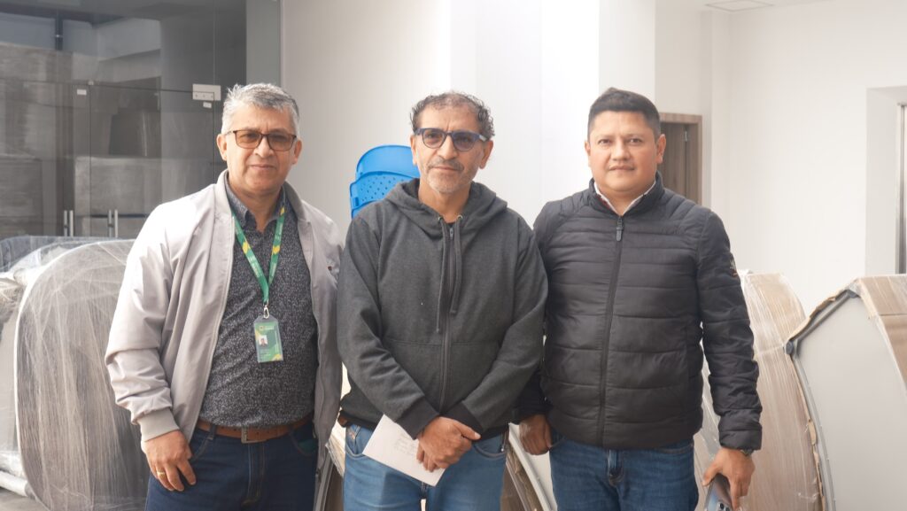 Tres directivos de la Dirección Administrativa de Cultura de Nariño posan en la nueva Biblioteca Departamental, rodeados de mobiliario de biblioteca aún en sus cajas.