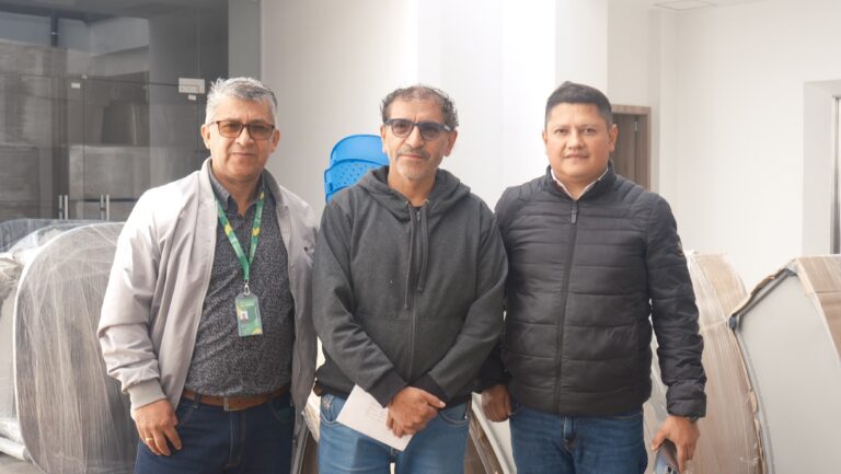 Tres directivos de la Dirección Administrativa de Cultura de Nariño posan en la nueva Biblioteca Departamental, rodeados de mobiliario de biblioteca aún en sus cajas.
