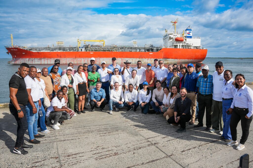 Foto grupal de la delegación de la Unión Europea, el Gobernador Luis Alfonso Escobar, autoridades locales y comunidades pesqueras posando en el muelle de Tumaco con un buque carguero de fondo.