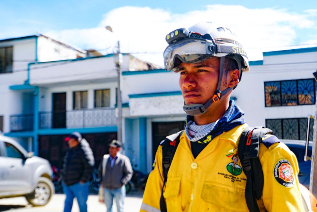 Retrato en primer plano de un bombero voluntario equipado con casco y linterna frontal durante la atención de la emergencia.