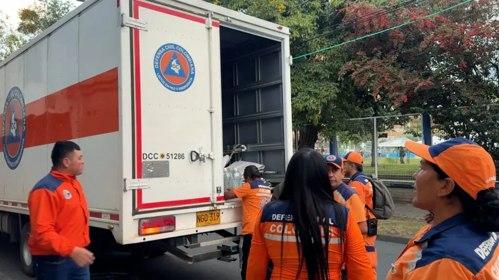 Voluntarios de la Defensa Civil Seccional Nariño cargando herramientas y equipos de socorro en un camión de transporte institucional.