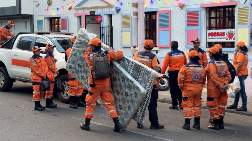 Integrantes del Grupo USAR Nivel Liviano de la Defensa Civil Nariño transportando colchonetas e insumos logísticos junto a una camioneta oficial.