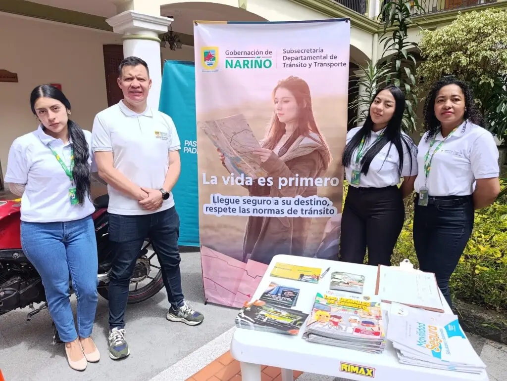 Cuatro integrantes del equipo de la Subsecretaría de Tránsito y Transporte posan junto a un pendón de la campaña "La vida es primero" y una mesa con folletos informativos.