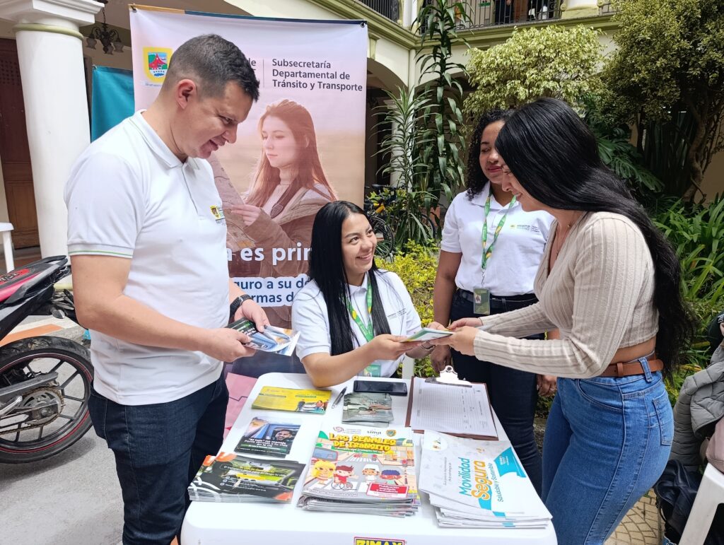 Funcionaria de la Subsecretaría de Tránsito entrega folletos educativos sobre movilidad segura a una ciudadana durante un evento institucional.