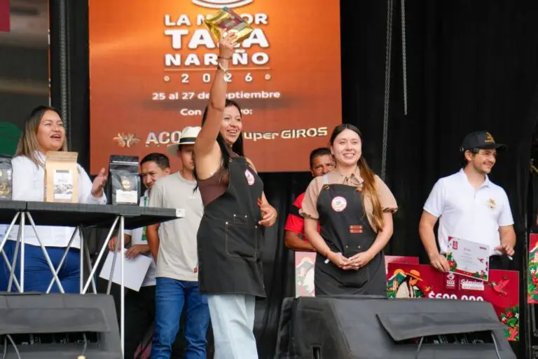 Productora de café celebrando con su paquete de café en alto durante la premiación de La Mejor Taza Nariño 2026 en Sandoná.