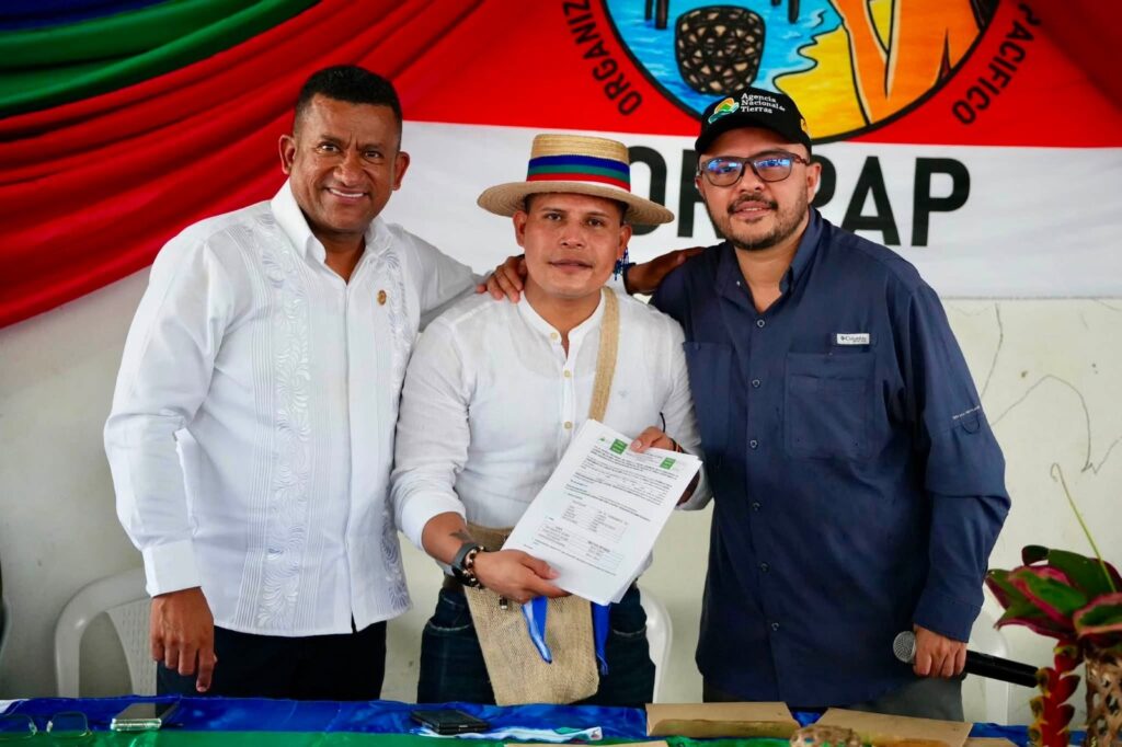 El gobernador Luis Alfonso Escobar Jaramillo y el director de la ANT Felipe Harman posan sonrientes junto a un líder indígena con sombrero tradicional que sostiene la resolución oficial de adjudicación de tierras.