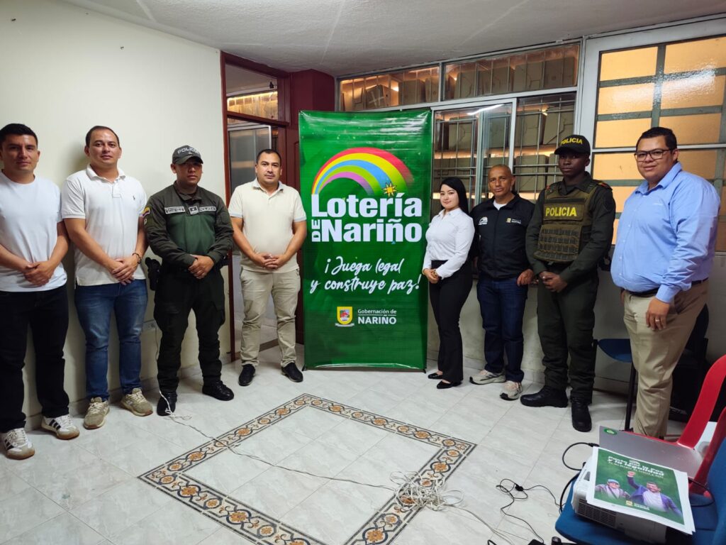 Delegados de la Lotería de Nariño, funcionarios municipales y uniformados de la Policía posando junto al pendón institucional.