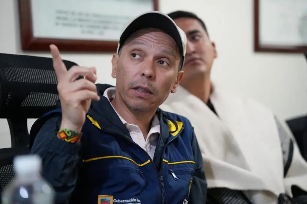 Gabriel Ocaña, Director Administrativo de Gestión del Riesgo de Desastres de Nariño, vistiendo gorra blanca y chaqueta institucional, gesticula con el dedo índice levantado mientras habla en la mesa de trabajo.