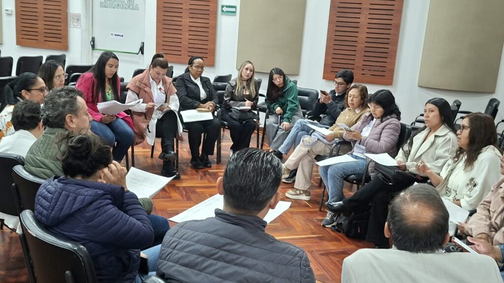 Integrantes de una mesa de trabajo reunidos en círculo analizando documentos durante el encuentro de educación ambiental en Nariño.