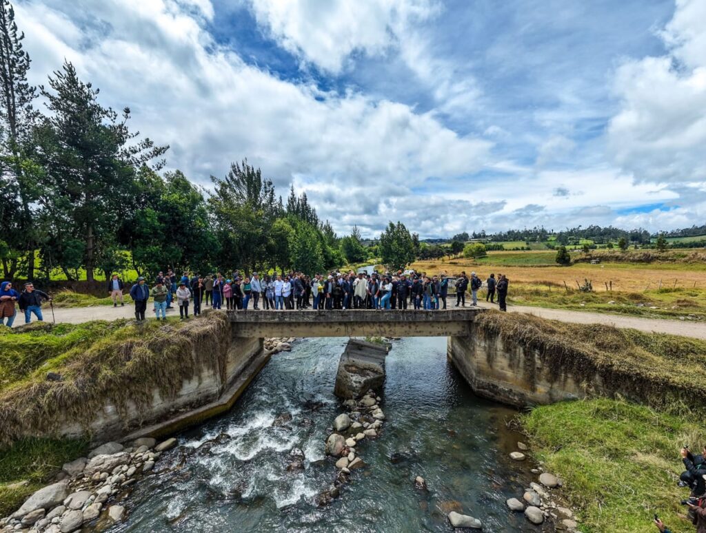 Gobernador de Nariño, autoridades locales y comunidad realizando inspección técnica sobre un puente de concreto que cruza un río en zona rural.