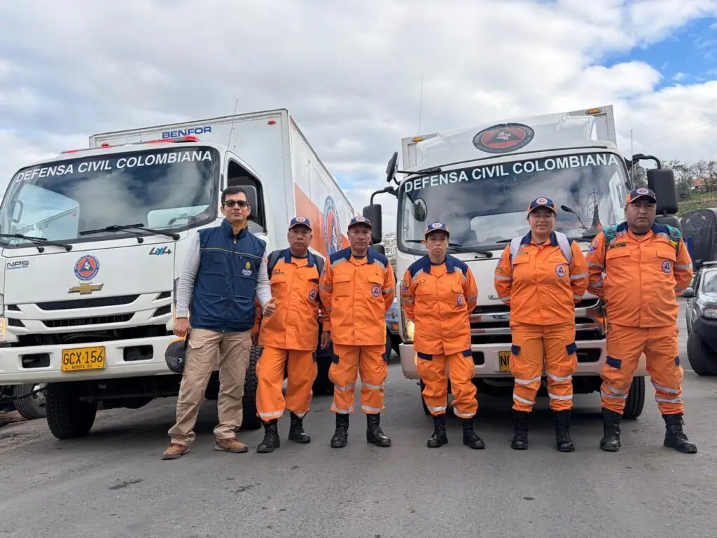 Gabriel Pérez, enlace de la UNGRD en Nariño, junto al equipo operativo de la Defensa Civil frente a los camiones de la caravana humanitaria.