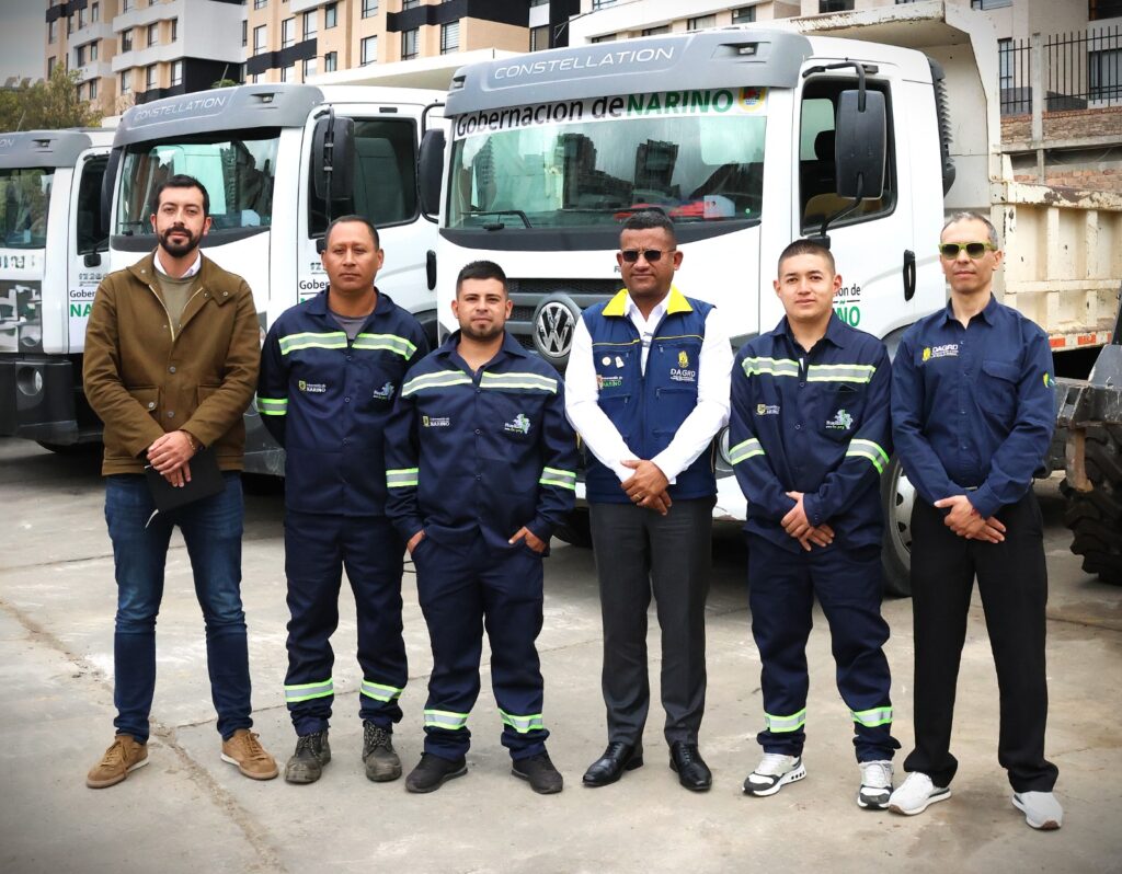 Equipo humano y personal de la DAGRD posan de pie frente a las volquetas de la Gobernación de Nariño destinadas a la atención de la emergencia.