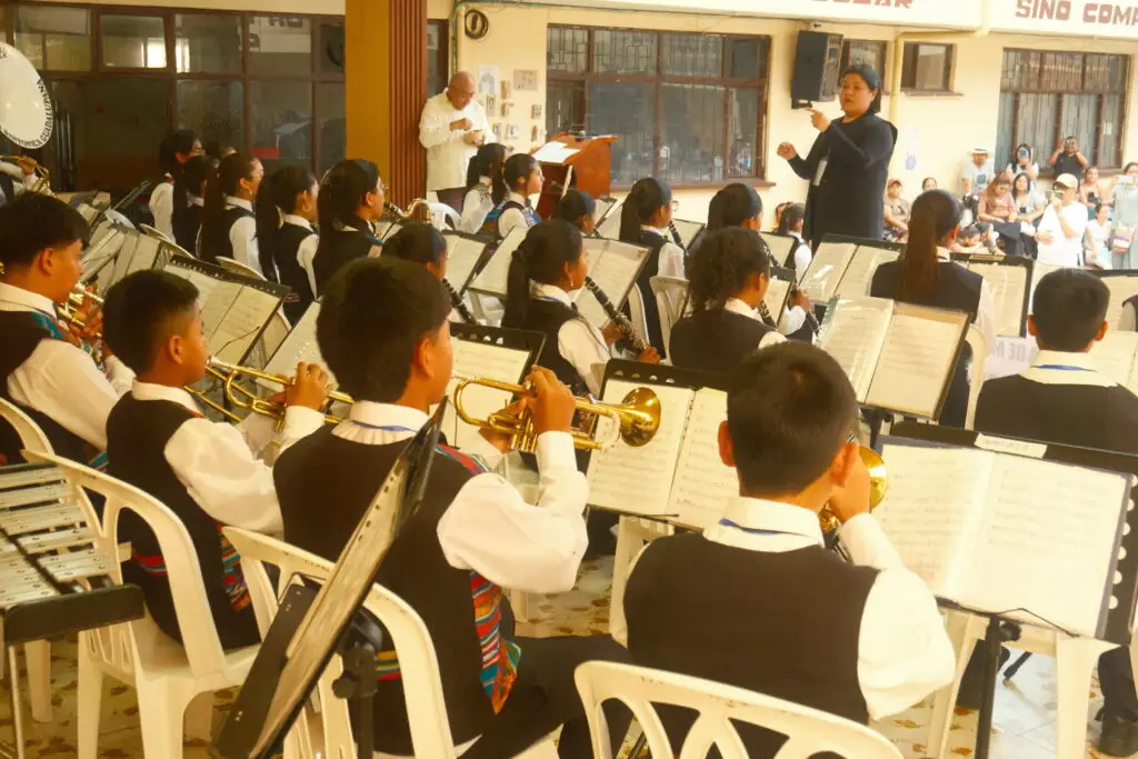 Integrantes de una banda musical infantil interpretando sus instrumentos bajo la guía de una directora durante el concurso en Samaniego.