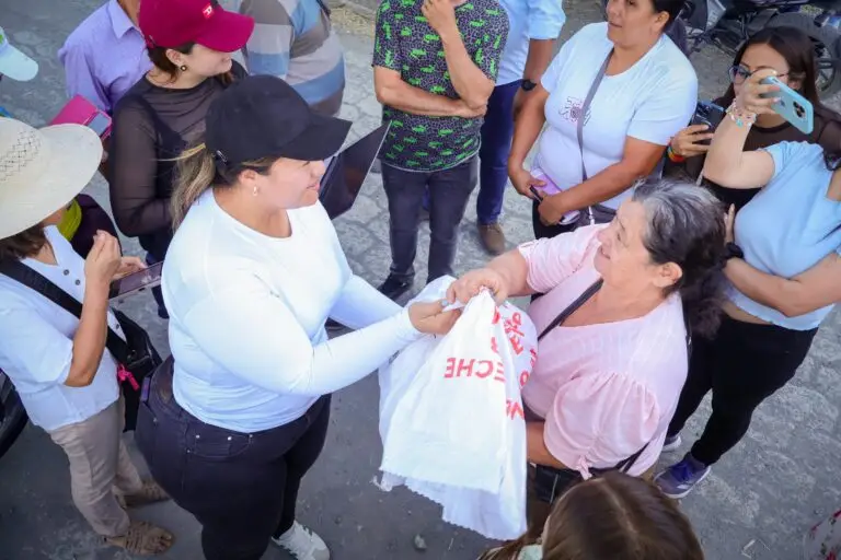 Una joven con gorra negra y camiseta blanca entrega un paquete de ayuda a una mujer mayor con blusa rosada durante la jornada en Ancuya.