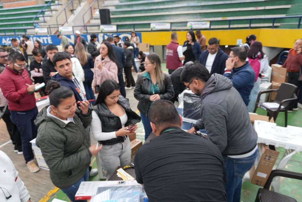 Grupo de representantes y delegados municipales recibiendo equipos de dotación para las Casas para la Dignidad de la Mujer en un coliseo.  