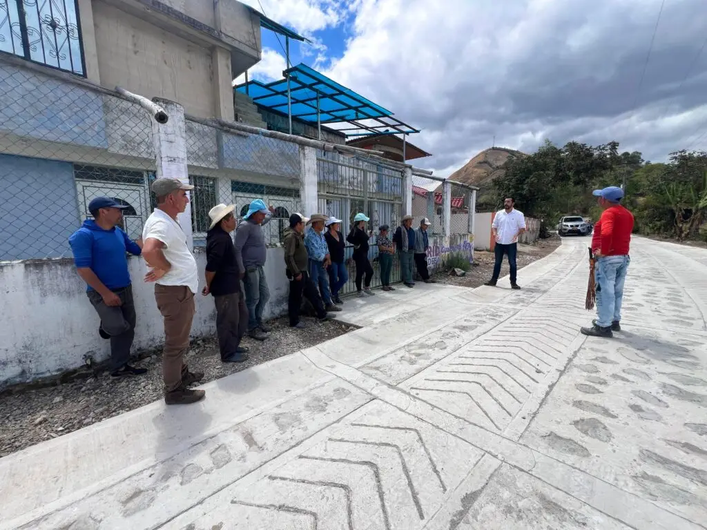 Funcionario dialogando con un grupo de habitantes rurales al borde de un tramo recién construido de placa huella en el departamento de Nariño.